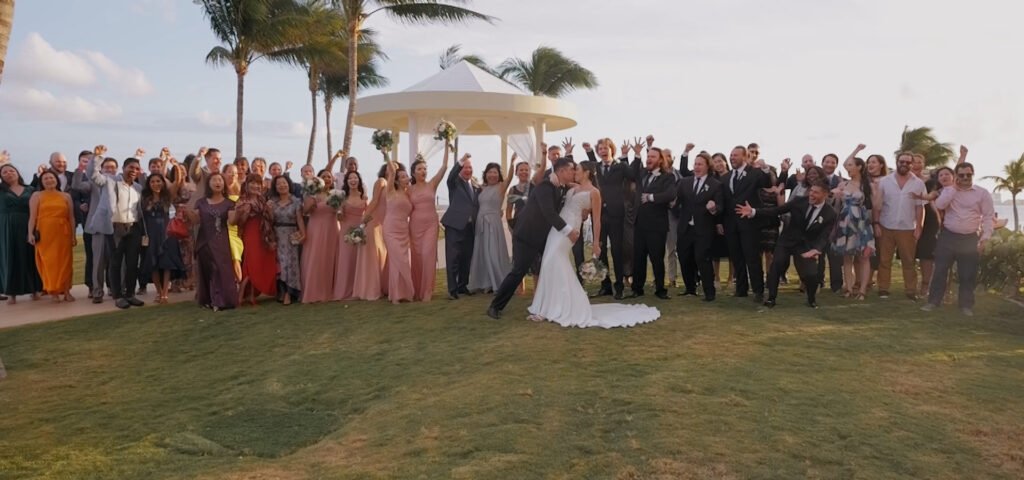 n la calidez de un día inolvidable, los recién casados se funden en un dulce beso, rodeados de la alegría y el amor de su familia y amigos. En medio de la celebración, sus sonrisas brillan aún más brillantes que el sol, capturando un momento que será recordado por siempre en sus corazones.